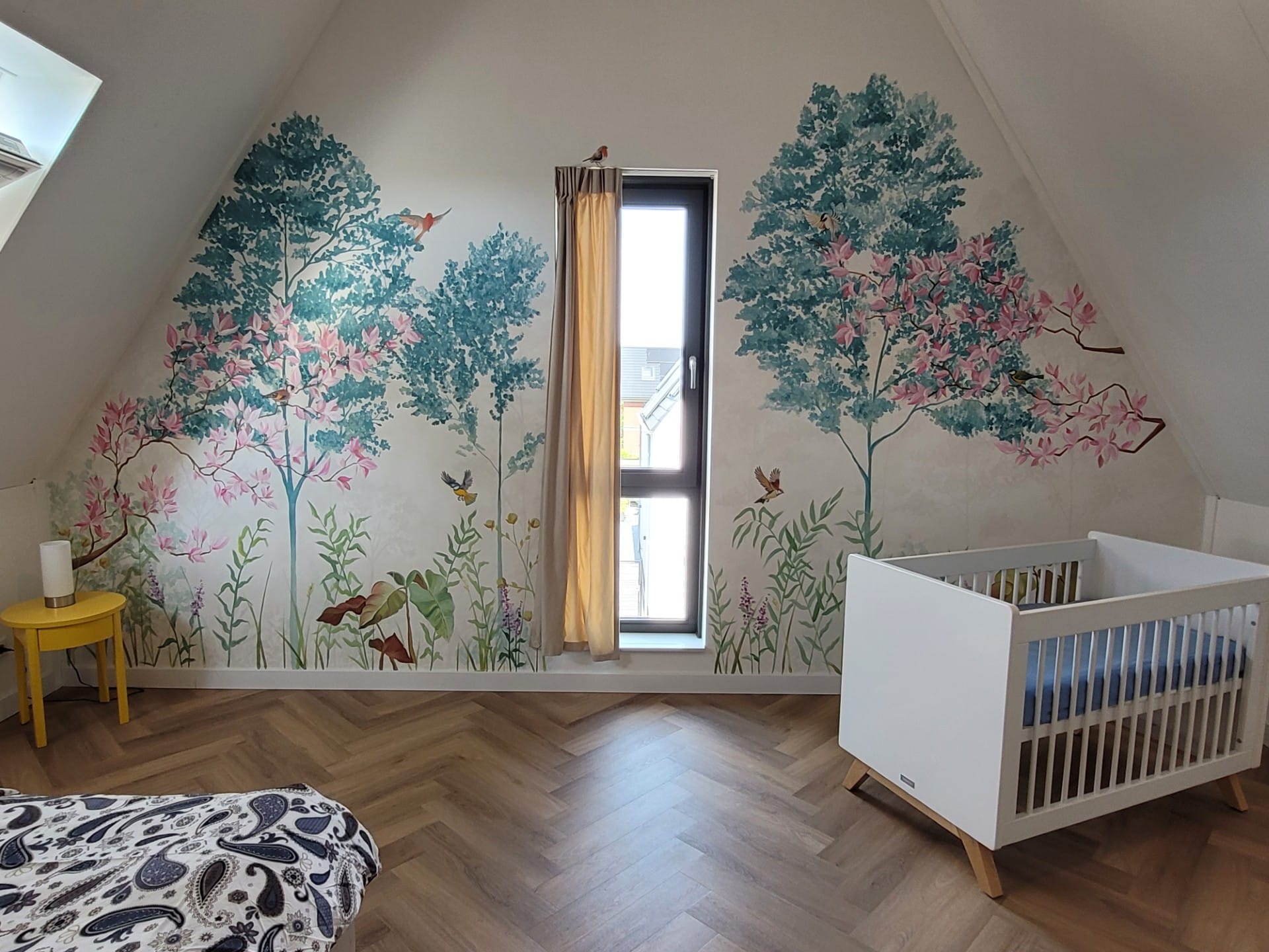 Handgeschilderde muurschildering met bomen en vogels in een babykamer